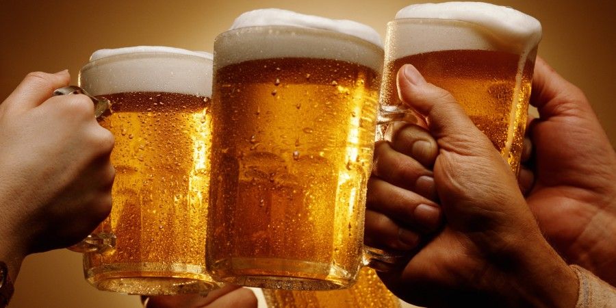FOUR HANDS MALE AND FEMALE TOAST WITH MUGS OF BEER