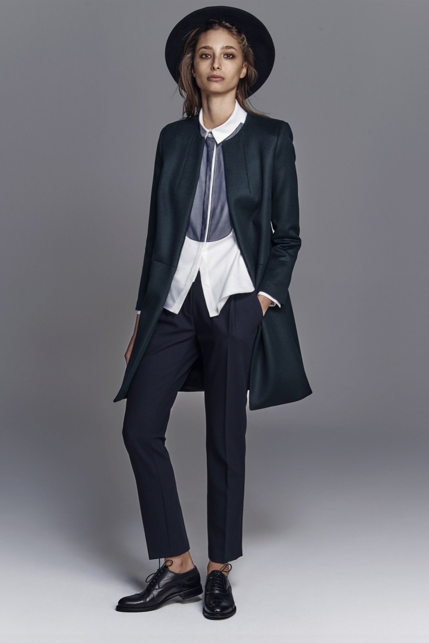 Look tomboy: pantaloni da uomo, gilet, camicia fuori e cappotto, con cappello a falde larghe