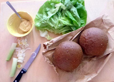 hamburger in preparazione, pane di segale, crema di senape, insalata e cipolotti