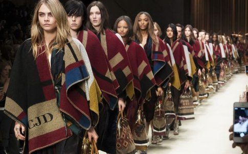 La sfilata Burberry Prorsum F/W 2014-2015 con il lancio del poncho con le iniziali cubitali della modella Cara Delevigne