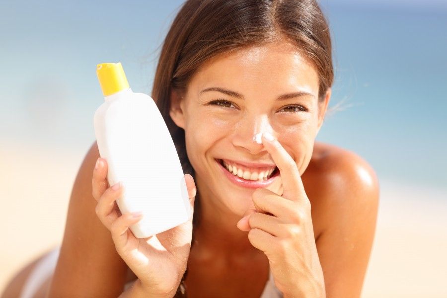 Suntan lotion woman applying sunscreen solar cream