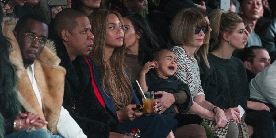 Kim Kardashian attempts to calm her daughter, North, as they watch a presentation of Kanye West's Fall/Winter 2015 partnership with Adidas at New York Fashion Week