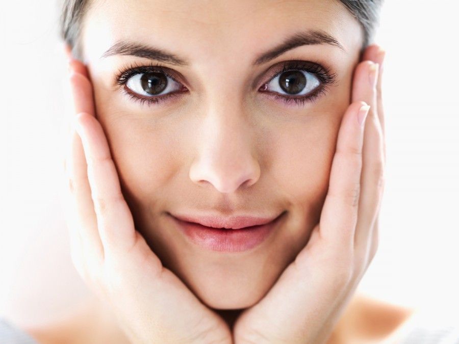 Closeup portrait of a charming young woman holding her face with hands