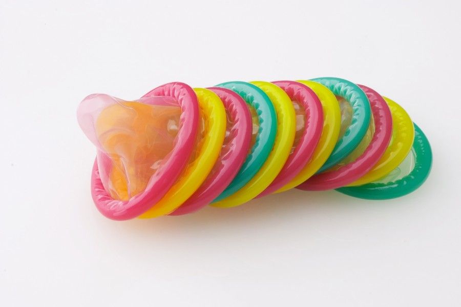 many colored condoms on white background - viele farbige kondome vor weissem hintergrund