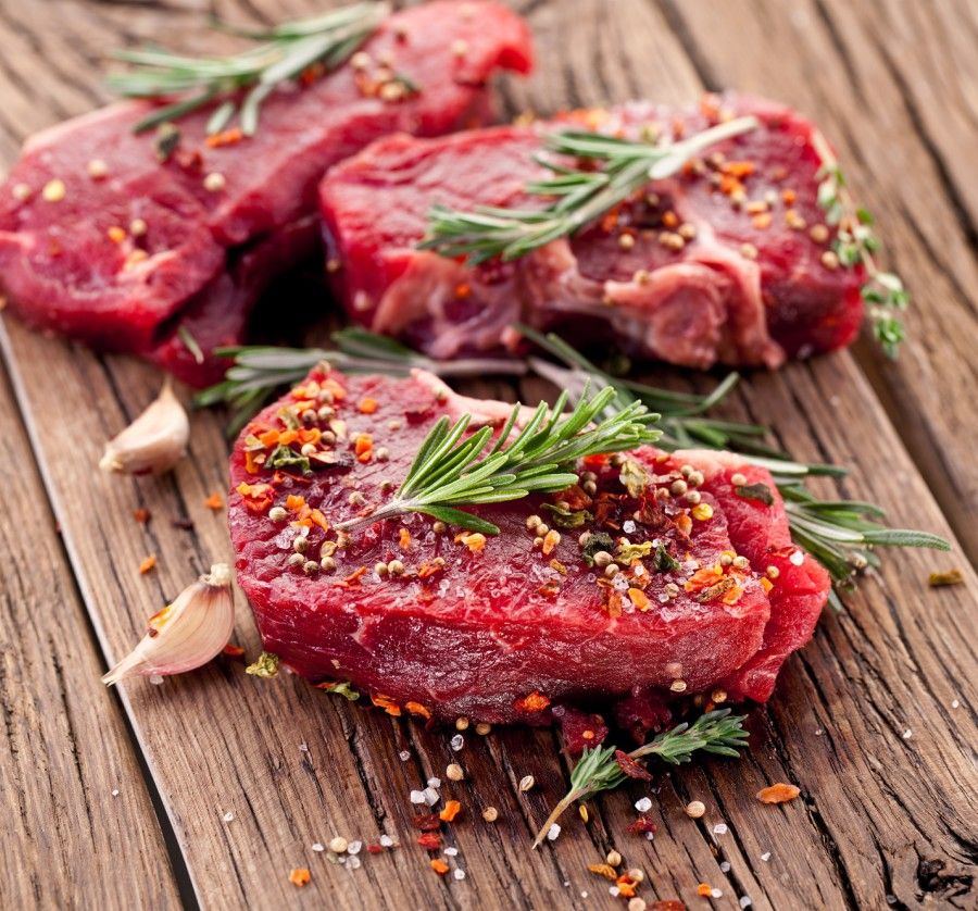 Raw beef steak on a dark wooden table.