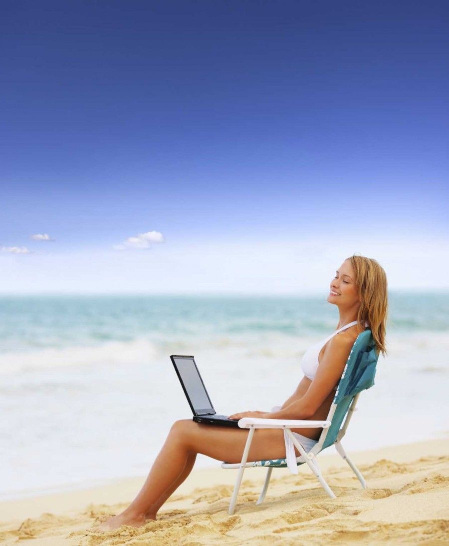 Beautiful woman on the beach with a laptop computer. This is taken at Bellows (Closed military beach) in Hawaii. One of the most beautiful beaches in the world!