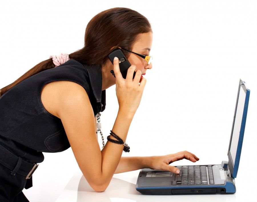 Young Girl Talking On The Telephone And Using A Notebook Computer