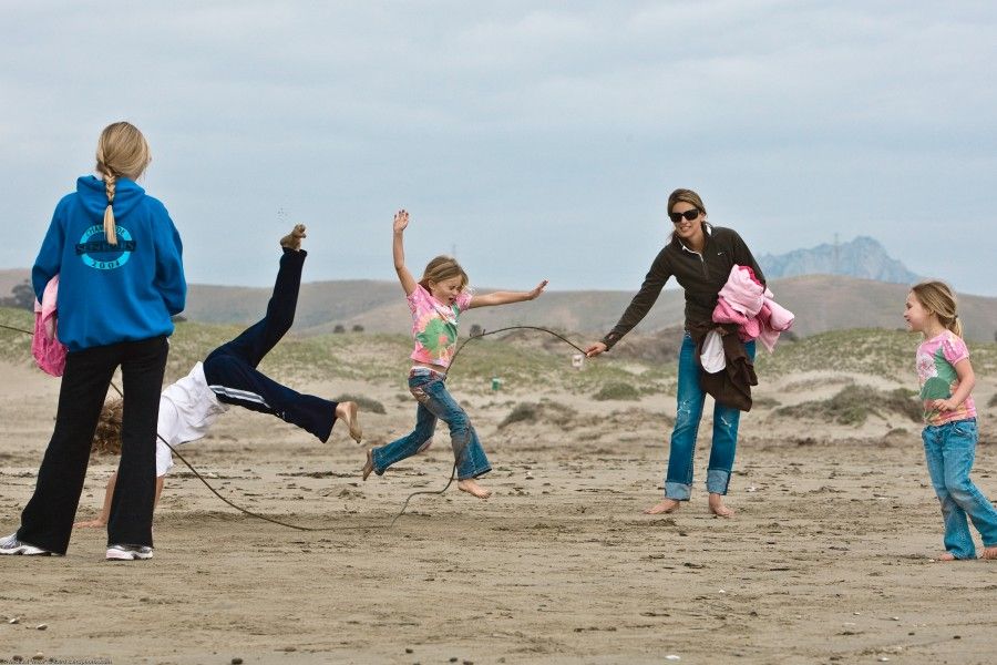 Kids play on Morro Strand State Beach by skiping rope which actually is a giant kelp strand