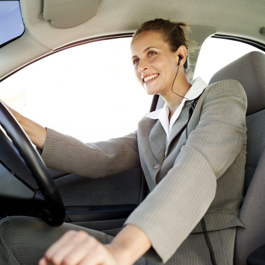 Woman Driving a Car and Wearing Earphones --- Image by © Royalty-Free/Corbis