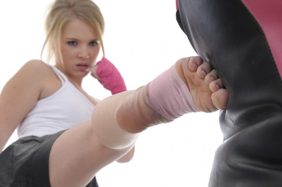 Kickboxer kicking a focus shield (focus is on the foot).