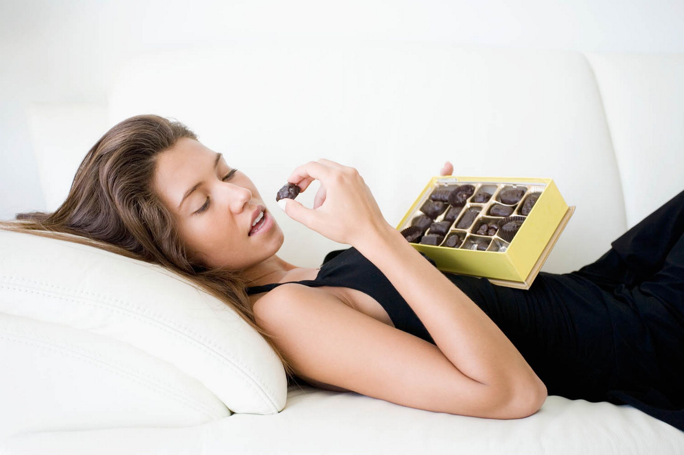 Сон ем шоколад. Девушка лежит и ест. Девушка в шоколаде. Девушка лежит на диване и ест. Девушка ест шоколад.