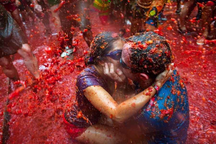 BUNOL, SPAIN - AUGUST 28:  Two Revellers kiss each other covered in tomato pulp while participating the annual Tomatina festival on August 28, 2013 in Bunol, Spain. An estimated 20,000 people threw 130 tons of ripe tomatoes in the world's biggest tomato fight held annually in this Spanish Mediterranean town.  (Photo by David Ramos/Getty Images)