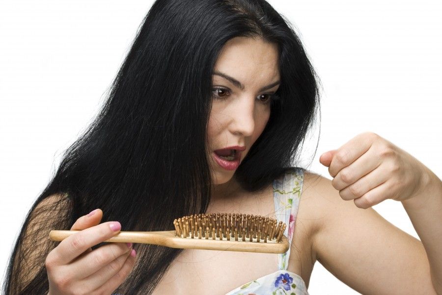 Shocked woman making a face because losing hair on hairbrush isolated on white background