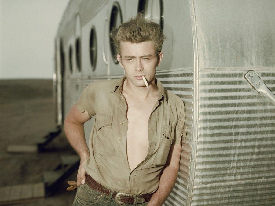 James Dean leans against his dressing room trailer on the set of the film Giant