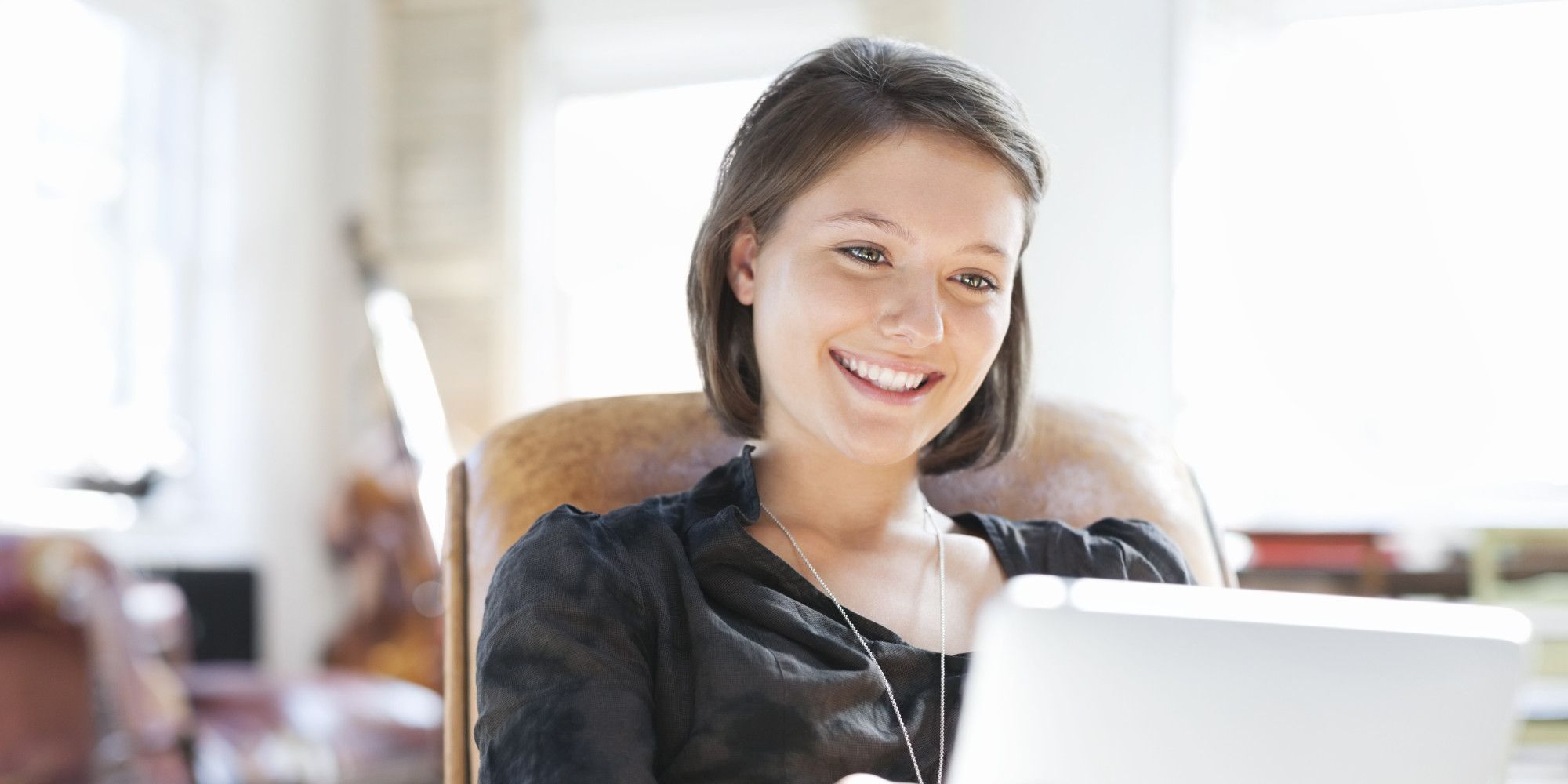 Young woman relaxing in chair using digital tablet