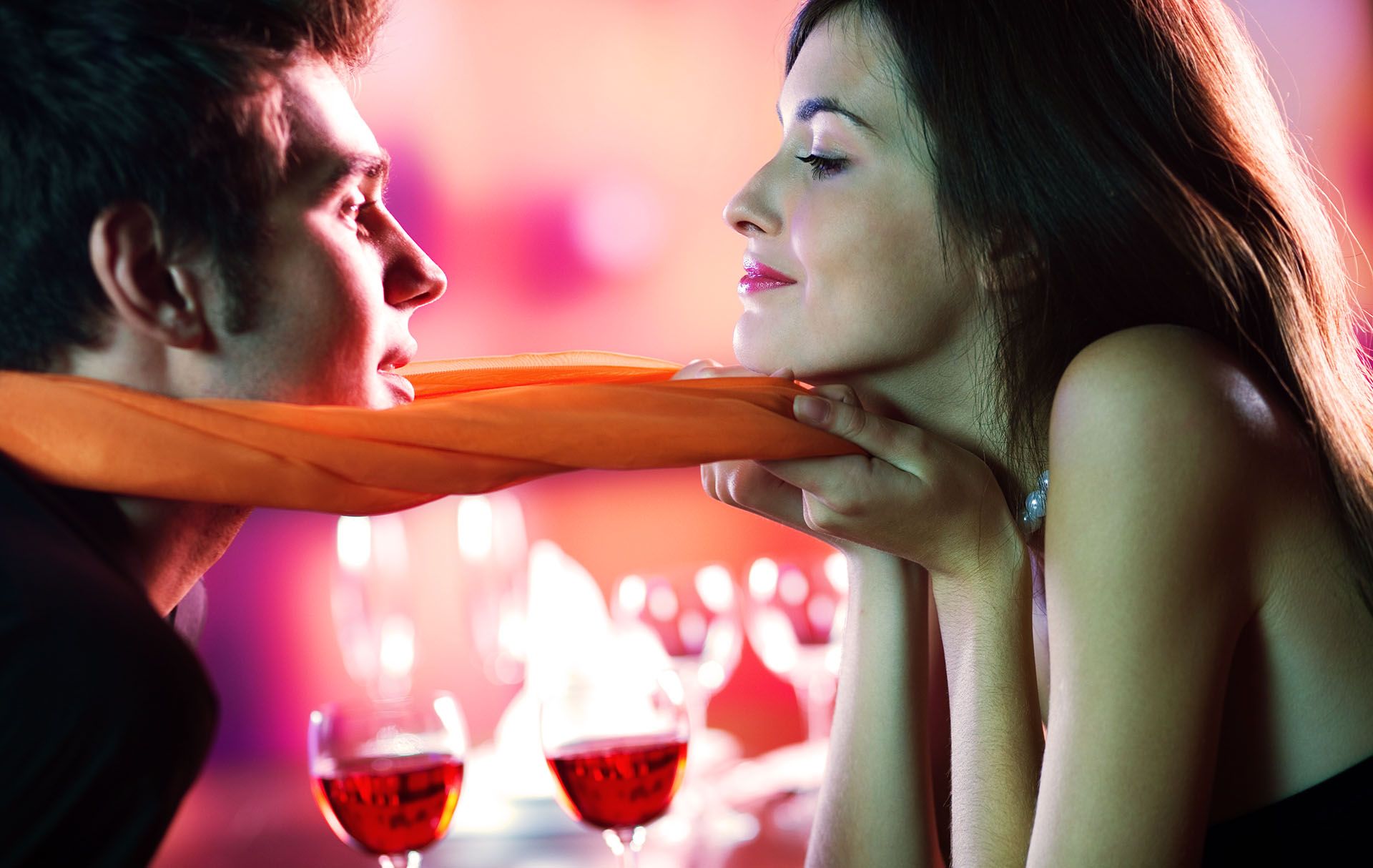 Young attractive happy couple kissing in restaurant, celebrating or on romantic date
