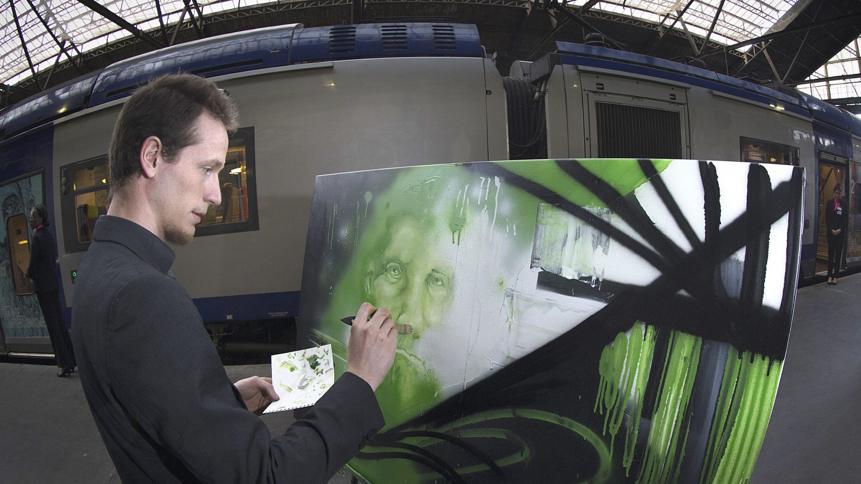 Rouen artist Bastiste Gateau paints as he stands on the platform of the St Lazare train station in Paris on April 18, 2015,  from where the "Impressionism Trains" will start it journey every weekend until the end of September, linking Paris to Giverny, the home of French Impressionist artist Claude Monet.   AFP PHOTO / JOEL SAGET