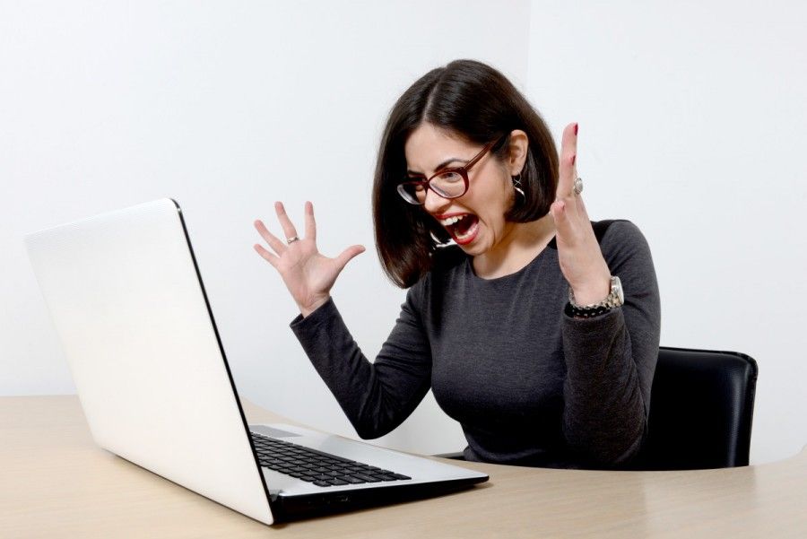 Young beautiful stressed businesswoman screaming at laptop