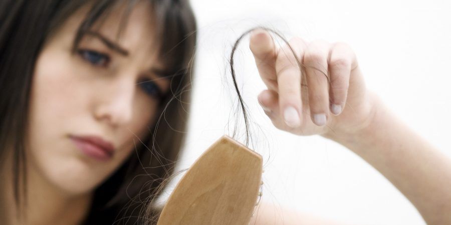 Portrait of a young woman brushing her hair, close up (studio)