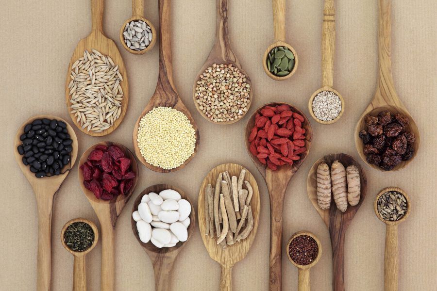 Dried super health food selection in wooden spoons over natural paper background. High in antioxidants, minerals, vitamins and dietary fiber.