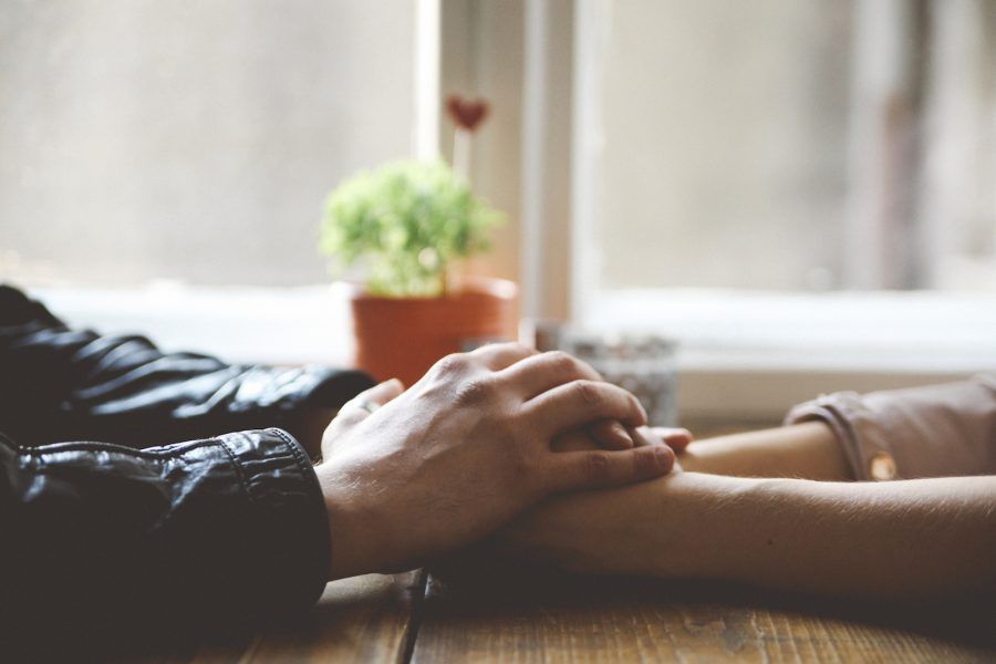 Close up of man and woman's hands holding together in a cafe. Flirting, romanticising, making out concept. Shot with large aperture lens in shallow focus.