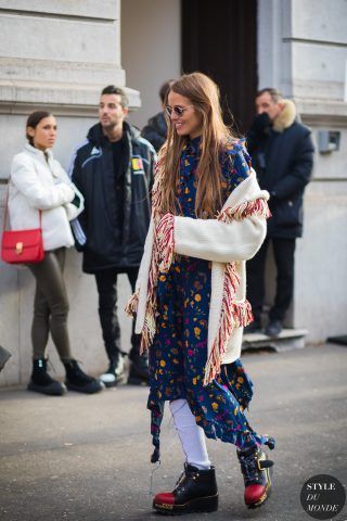 Carlotta Oddi con improbabili stivaletti indossati con calzini tubolari e abbinati ad un abito a stampa e maglione con frange.