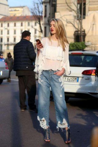 Un look composto da una blusa con ruches di tendenza, un jeans con ricami e sandali con tacco.