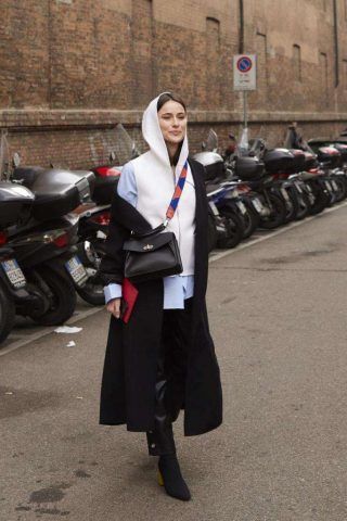 Sovrapposizioni di vari capi di abbigliamento e cappotto indossato in modo asimmetrico.