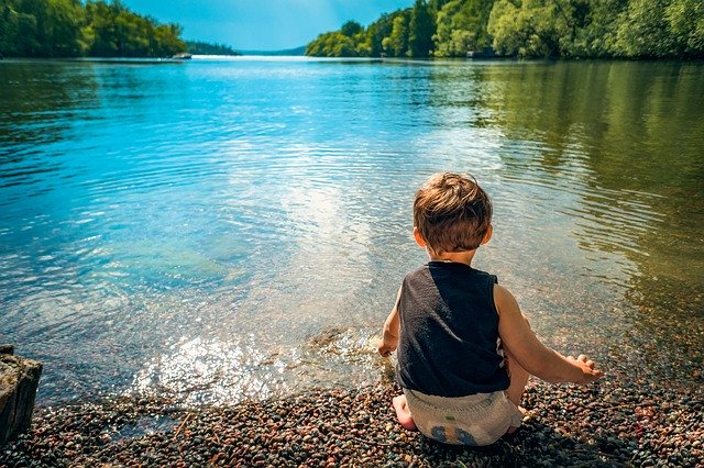 Bambino seduto in riva al lago