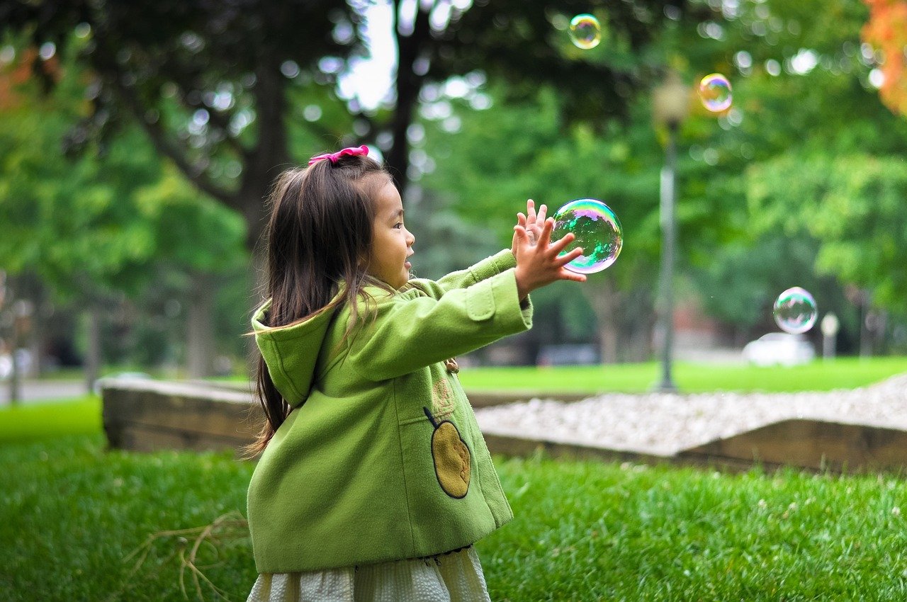 Bambina gioca al parco con le bolle