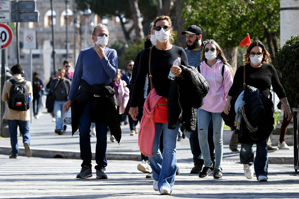 Persone camminano in strada con la mascherina